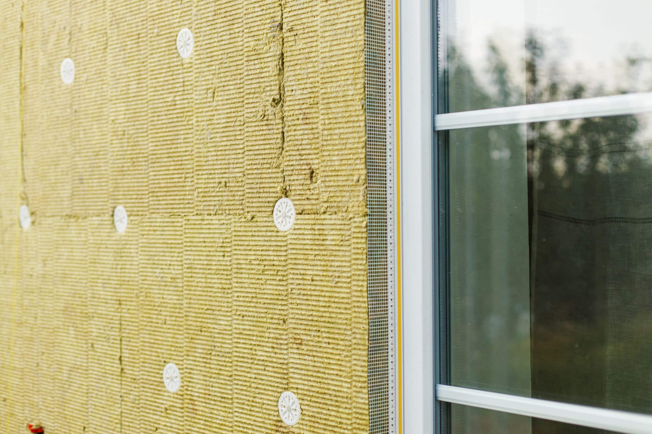 Gros plan sur la pose d'isolant extérieur avec chevilles de fixation sur une façade